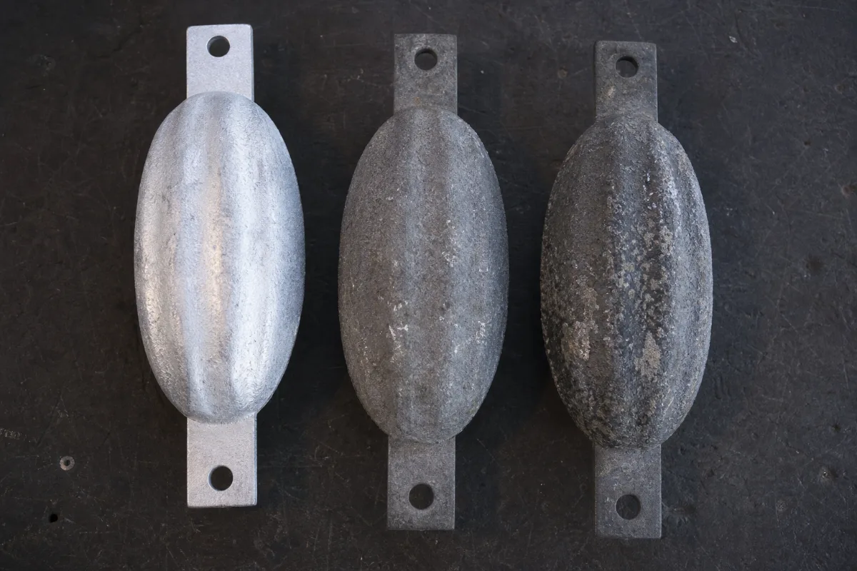 Three sacrificial anodes of different alloys arranged side by side on a workbench.