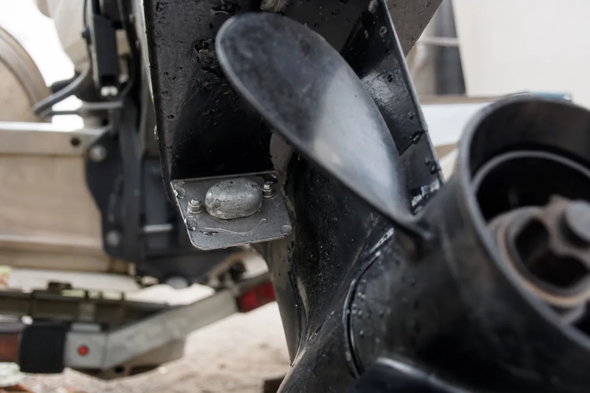 The trim tab anode behind the propeller of a tilted outboard motor.