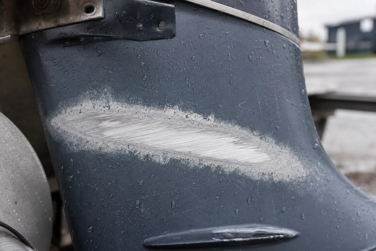 A deep scratch through the paint on an outboard lower unit with corrosion starting around it.