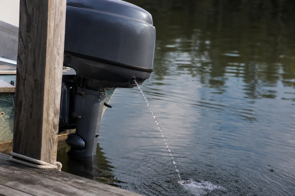 A steady stream of cooling water shooting out of the tell-tale hole on a running outboard beside a dock.
